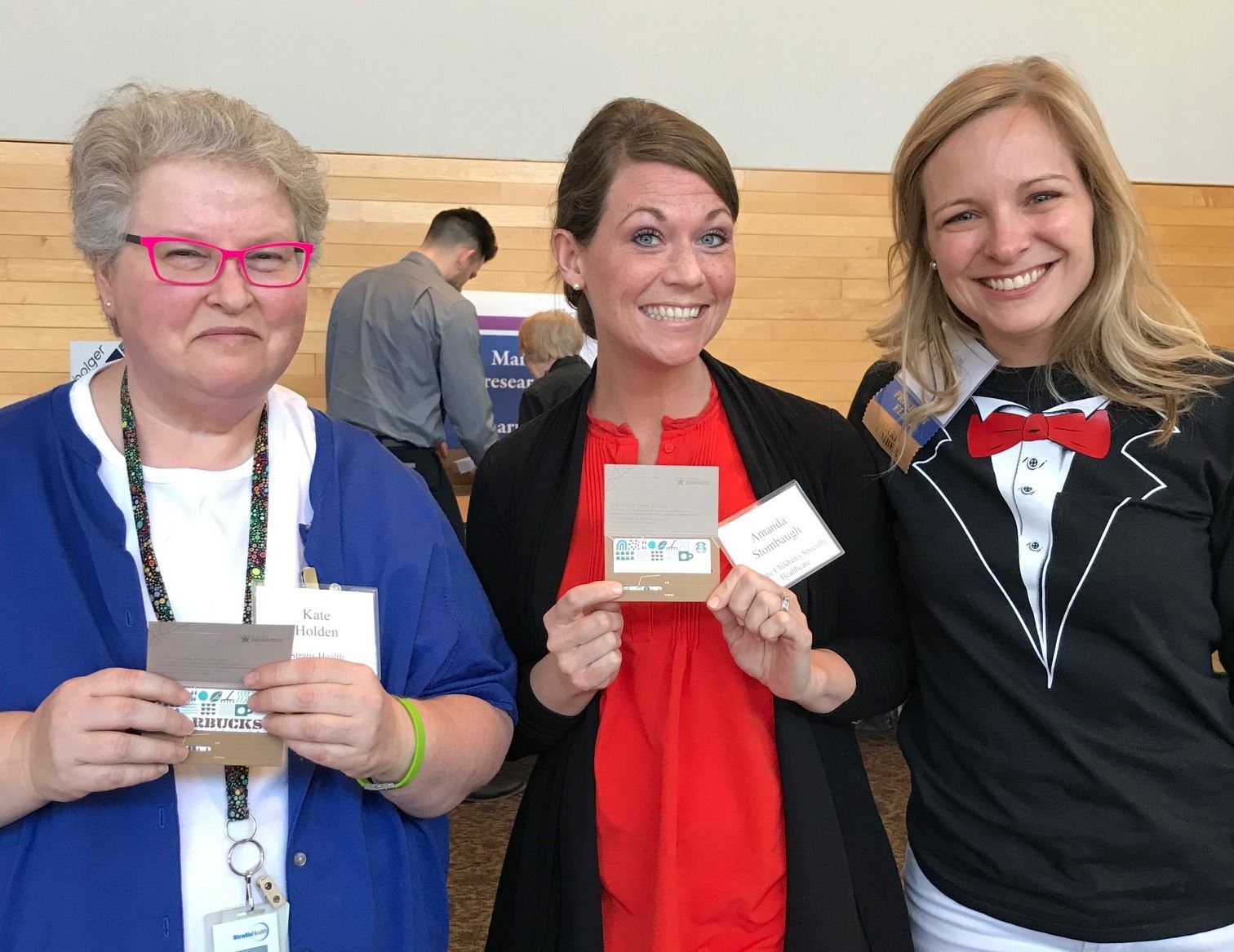 Cassi wears a tuxedo t-shirt as she interacts with two MHSCN members who are showing off some prizes.